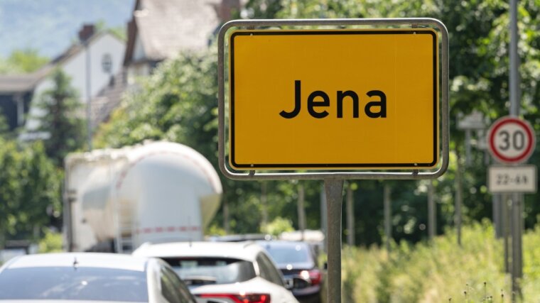 Fahrzeuge fahren entlang eines Ortseingangsschildes (Jena)