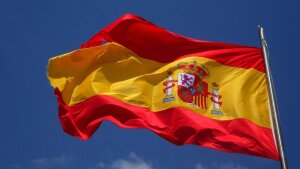 Die Flagge Spaniens weht vor einem fast wolkenlosen Himmel